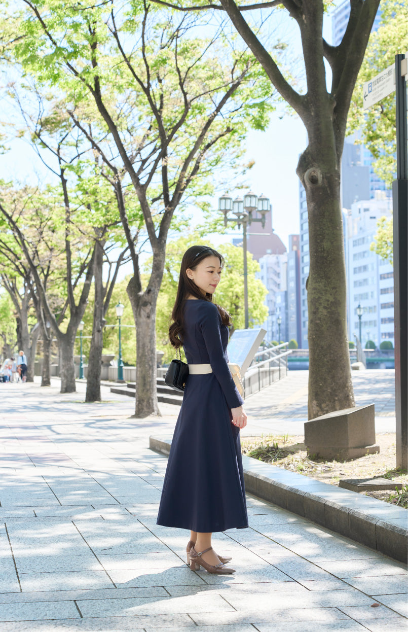 ネイビー色のリボン付き低身長ワンピースを着用したロケでの横姿