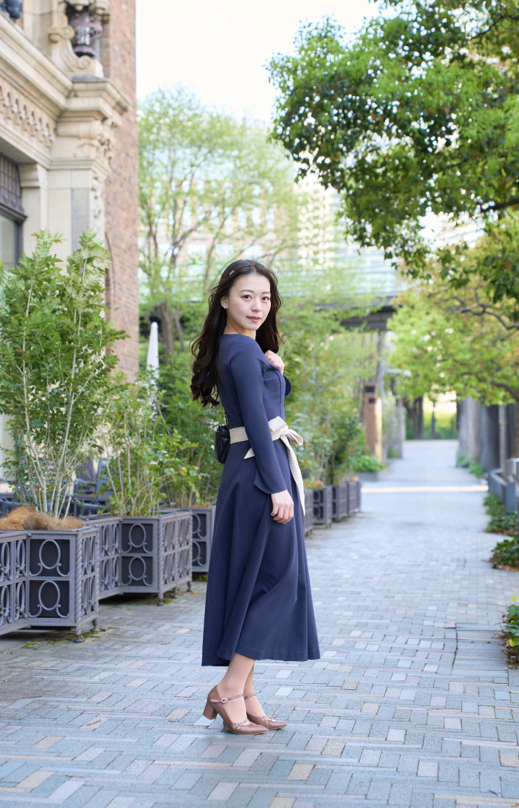 ネイビー色のリボン付き低身長ワンピースを着用したロケでの横姿