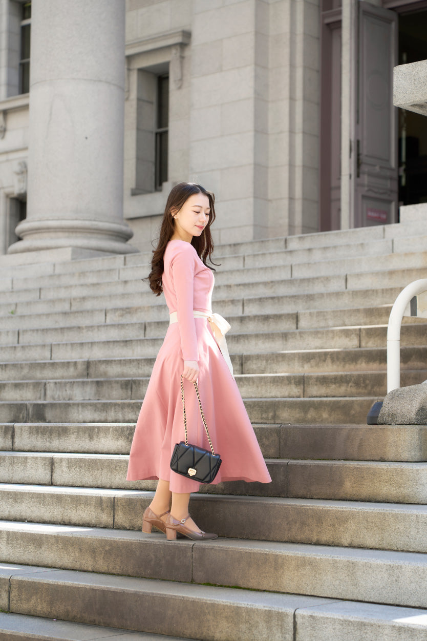 ピンク色のリボン付き低身長ワンピースを着用したロケでの横姿