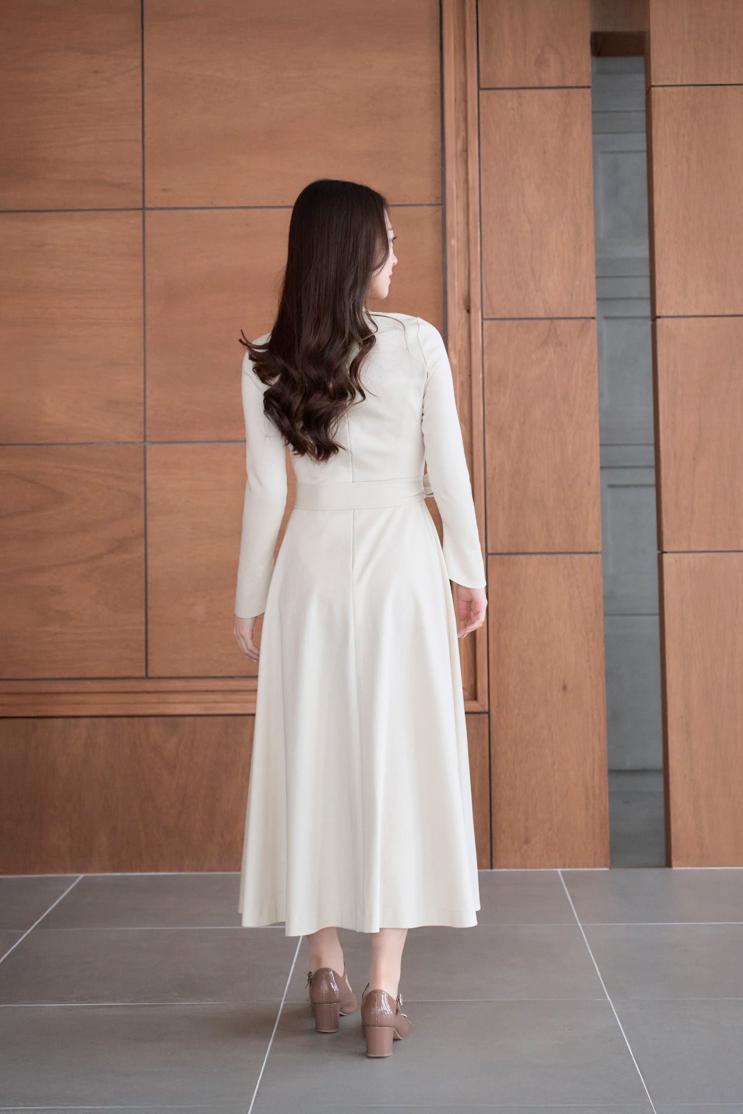 リボン付きのベージュ色低身長ワンピースを着用した後ろ姿