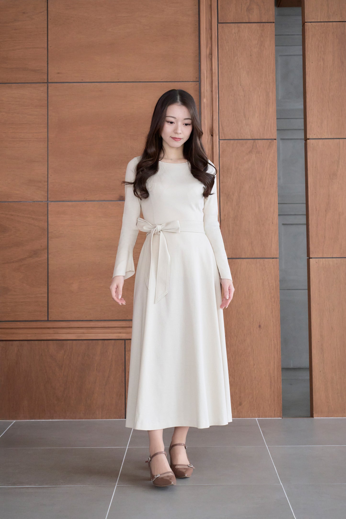 ベージュ色のリボン付き低身長ワンピースを着用した正面姿