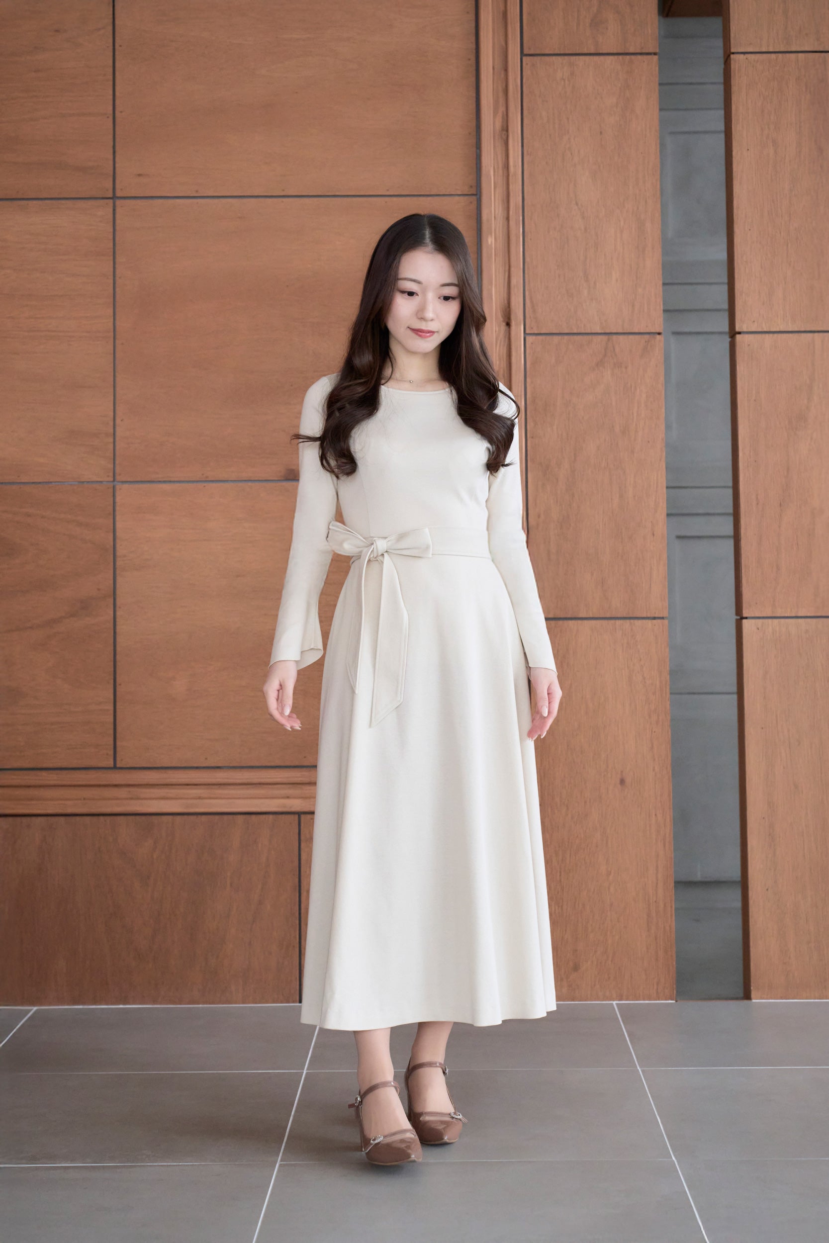 ベージュ色のリボン付き低身長ワンピースを着用した正面姿