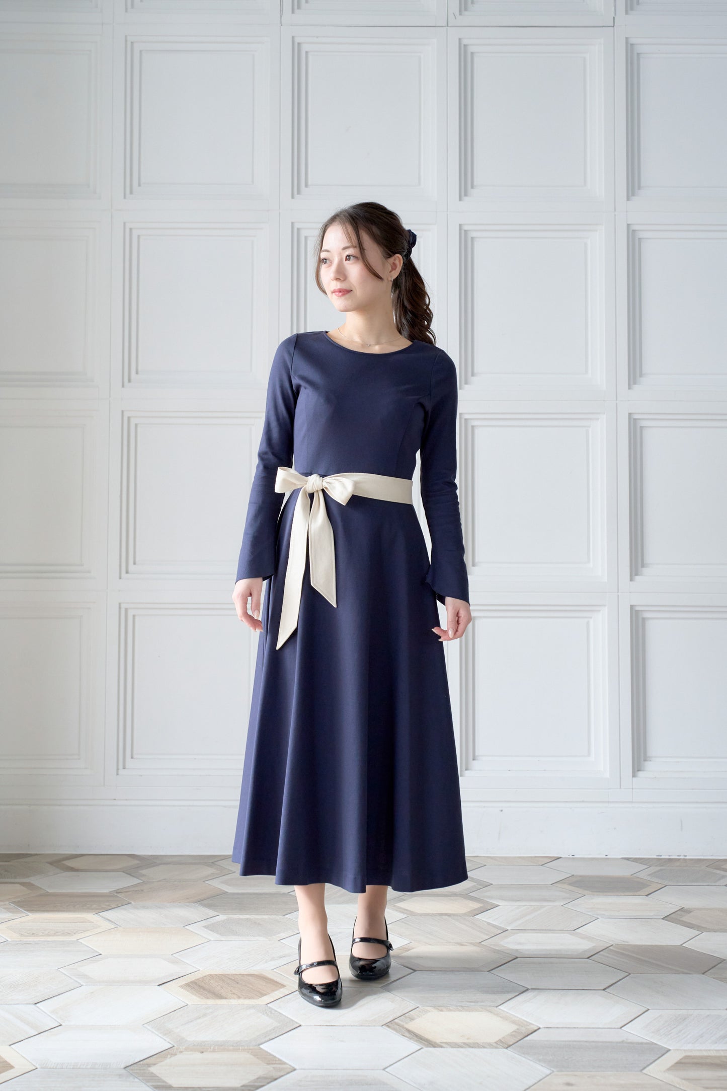 リボン付きのネイビー色低身長ワンピースを着用した正面姿